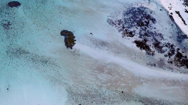Luftaufnahme von t&uuml;rkisfarbenem arktischem Wasser mit Blick nach unten, &Uuml;bergang zu schneebedeckter Insel in Nordnorwegen, Drohne steigt auf, 4K
