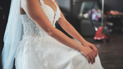 Bride in elegant white lace wedding dress sits calmly before the ceremony.