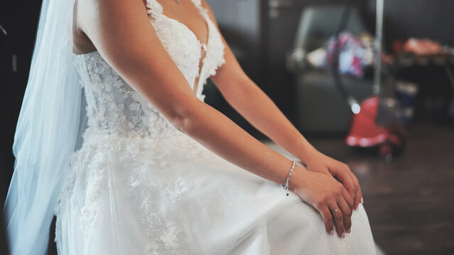 Bride in elegant white lace wedding dress sits calmly before the ceremony.