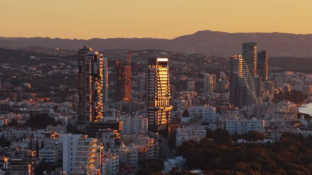 Aerial drone view of twin high rise towers along the Limassol waterfront at sunset