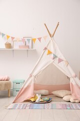 Cute wigwam with pillows, books and toys in stylish child's room © New Africa
