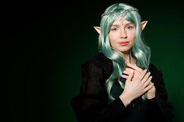 Obraz premium Beautiful girl dressed as elf on dark green background, space for text
