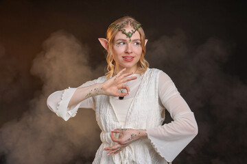 Obraz premium Beautiful girl dressed as elf on black background with smoke