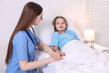 Obraz premium Doctor examining little child on bed in hospital