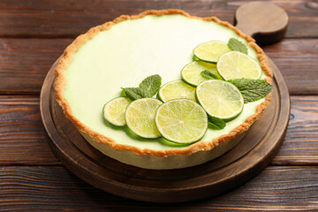 Tasty lime pie with fruit slices and mint leaves on wooden table, closeup © New Africa