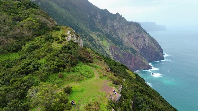Dramatic aerial view of Madeira's eastern coastline, where lush green cliffs meet the vibrant turquoise Atlantic, showcasing the island's wild, untamed beauty. Vereda do Larano