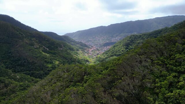Dramatic aerial view of Madeira's eastern coastline, where lush green cliffs meet the vibrant turquoise Atlantic, showcasing the island's wild, untamed beauty. Vereda do Larano