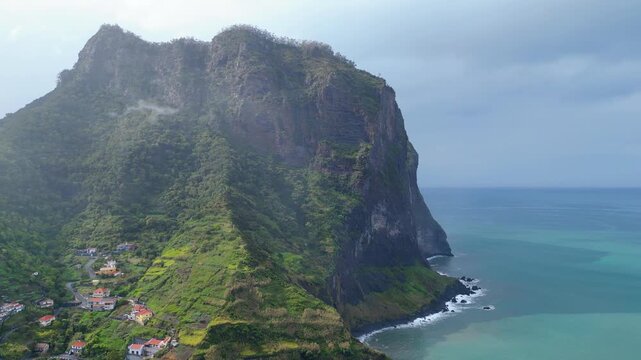 Dramatic cliffs, a charming coastal village, and a stunning waterfall meeting the Atlantic Ocean in Madeira. A breathtaking blend of nature and human settlement. Porto da Cruz
