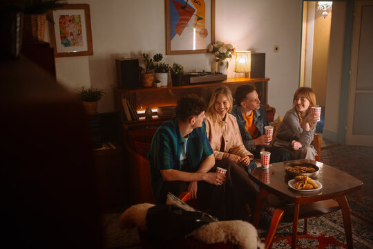 Friends Enjoying Cozy Gathering with Snacks and Drinks in Stylish Living Room