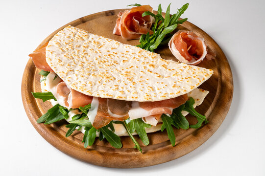 Piadina romagnola with squacquerone cheese, prosciutto and arugula, traditional Italian flatbread sandwich