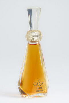 Cologne, Germany March 28 2024: Elegant prism-shaped glass bottle of Carat Eau de Parfum by 4711 Muelhens. Vintage fragrance with golden liquid, isolated on light grey.