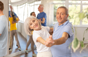 Fototapeta premium Happy aged woman learning to dance Viennese waltz with partner in dancing class. Active hobby of older generation concept