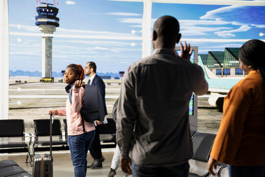 Waving goodbye at departure gate, sad proud parents, teen child studying abroad, traveling alone and boarding at terminal gate. Supportive family bid farewell to solo traveler student.