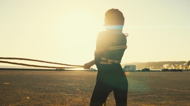 Woman silhouette dancing with a rope at sunset