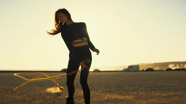 Silhouette of a woman performing with a rope at sunset