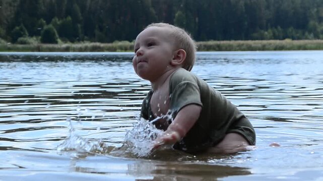 Happy toddler child on the beach, lake sea. Crawling along the shore along the water. 8 month old baby playing outside near the water. Summer vacation concept.