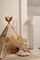 Stylish wigwam with dry leaves in child's room © New Africa