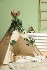 Cute wigwam with leaves and blanket in stylish child's room © New Africa