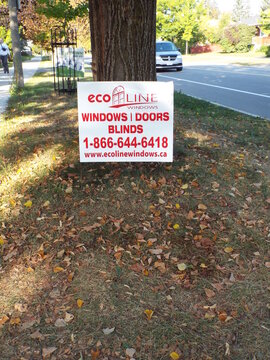 Vanier, Ontario, Canada &ndash; July 25, 2025: An "Ecoline Windows lawn" sign advertising windows, doors, and blinds stands beneath a tree at 518 Donald Street in Vanier.
