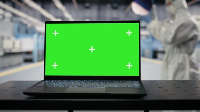 Green screen mockup laptop used by engineer in semiconductor factory with automated systems. Worker inspecting hardware in microchip industrial plant with chroma key notebook, camera B closeup