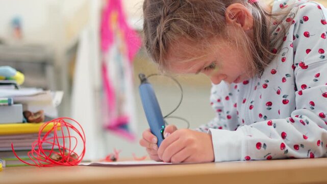 Cute girl using 3D pen on paper in study room at home. Female child creating artistic painting with modern technology on table