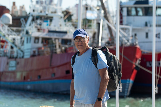 Medio cuerpo hombre mayor relajado y contento con paisaje naval de fondo con desenfoque