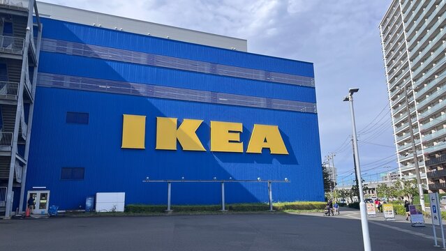 IKEA Tsuruhama store exterior featuring the iconic blue facade and yellow logo on a sunny day with pedestrians and neighboring apartment buildings - Osaka, Japan, October 15, 2024