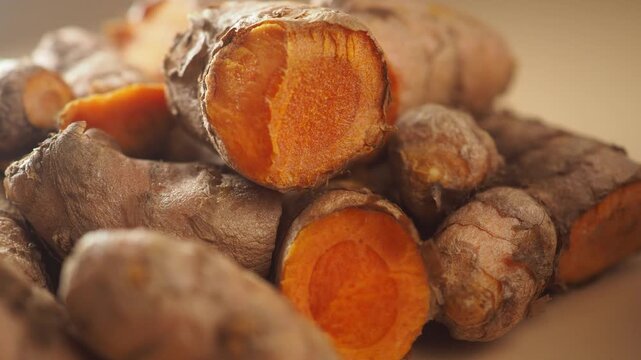 Close up shot of fresh turmeric root cut in half, showcasing its vibrant orange interior.