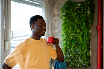 Fototapeta premium Young black man enjoying hot coffee by window