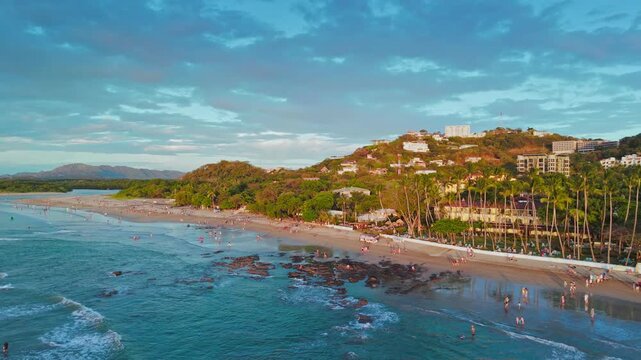Aerial landscape view of the town of Tamarindo in Costa Rica with Pacific Ocean, waves, coastline, tourists, homes and hotels climbing up the hills of the town
