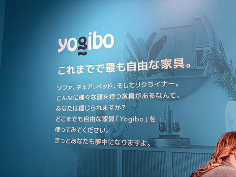Yogibo lifestyle furniture brand logo and advertising signage on a blue wall featuring Japanese text about versatile chairs and sofas - Tokyo, Japan, March 23, 2026
