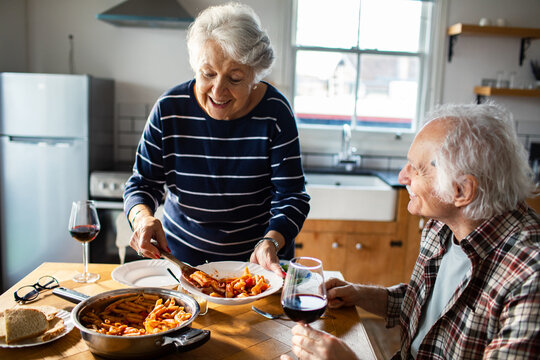 Senior couple sharing homemade pasta at kitchen table