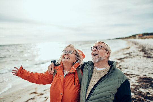 Happy senior couple walking on windy beach