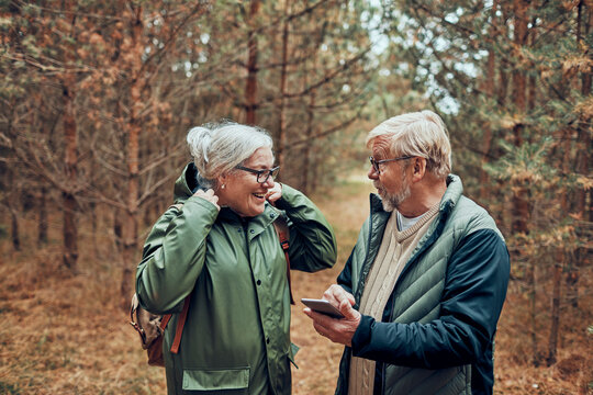 Senior couple using smartphone while hiking in forest