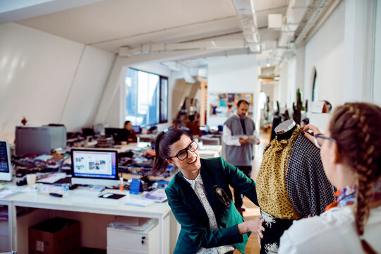 Two fashion designers collaborating on garment in open-plan studio