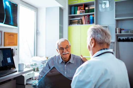 Senior man discussing x-ray with doctor in clinic