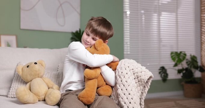 Little boy with his teddy bears on sofa at home