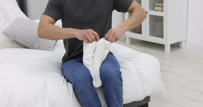 Man making funny monkey from towel on bed at home, closeup