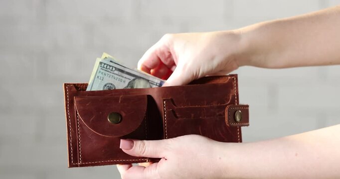 Woman showing wallet with money against white brick background, closeup