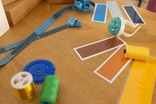 Planning sparking swatches fanning tape coiling pincushion holding pins spools lying on wood table