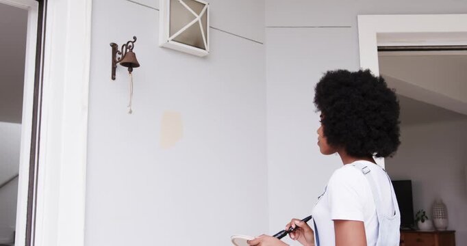 African American woman in white tee overalls holding brush tray testing swatch color, copy space
