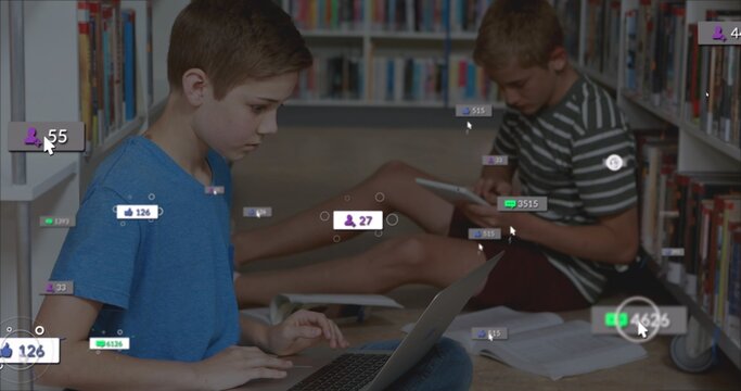 Sitting two boys working on laptop and tablet in library aisle, with notebooks and digital overlays