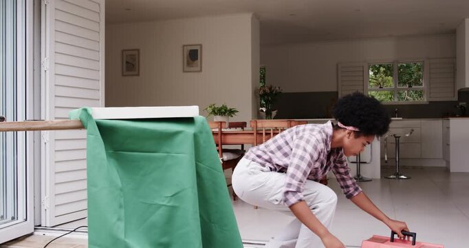 African American woman squatting, lifting pink black toolbox preparing workbench for repair