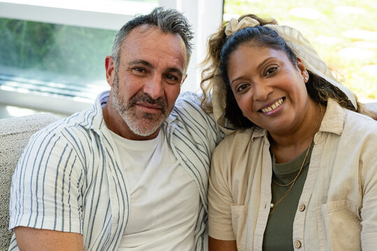Vertical video: Talking couple in stripes and beige top, camera cueing, sharing on sofa with window