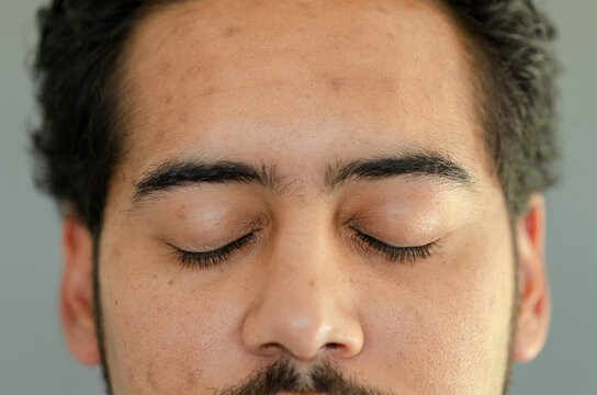 African American adult male closing eyes and showing trimmed facial hair and skin pores in studio