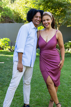 Vertical video: Smiling couple posing on lawn, camera clicking, wearing button-up and mauve dress