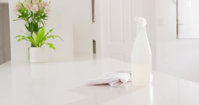 Subtle camera shift panning rightward, centering spray bottle and folded cloth on glossy counter