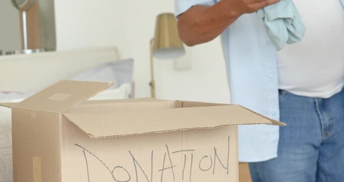 African American couple seeing donation box and packing clothing on bed, smiling