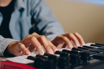 Person playing keyboard piano with focused hands on keys, creating music indoors with soft lighting and casual clothing, capturing moment of musical creativity and concentration © JK_kyoto