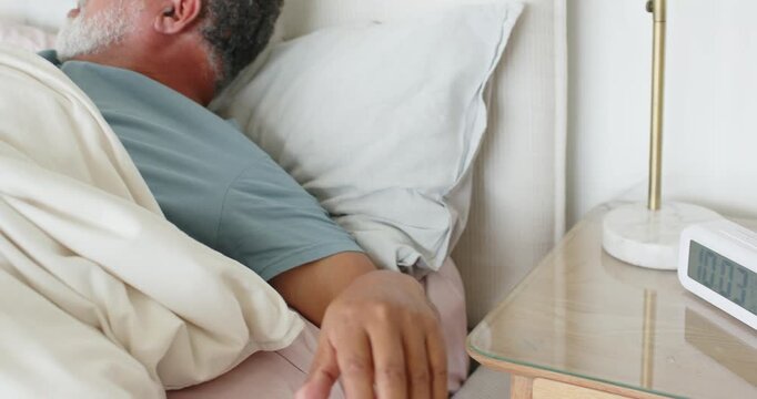 African American couple, man in light blue tee reaching digital clock, silencing alarm, sitting up